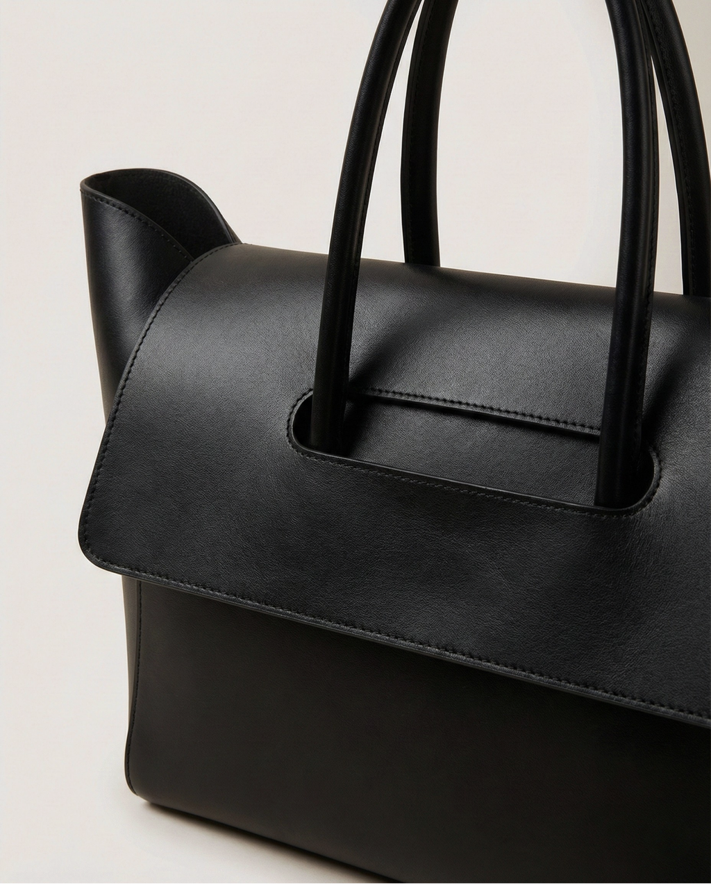 Black handbag with handles on a light gray background