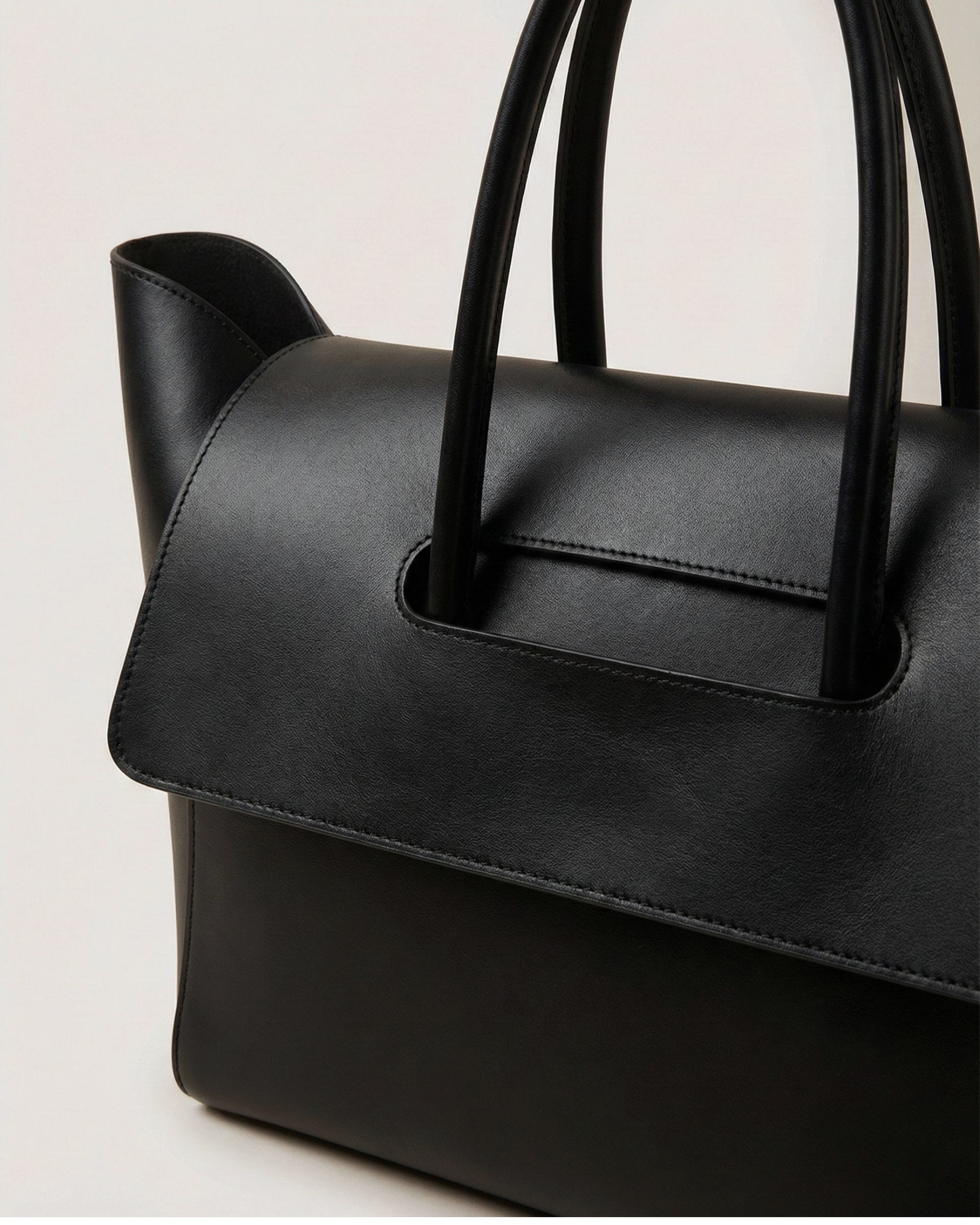 Black handbag with handles on a light gray background